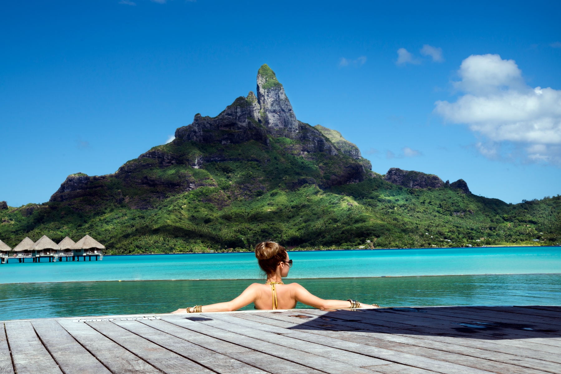 person resting by the pool in Tahiti with the view of a mountain. Tahiti is the ultimate dream vacation destination
