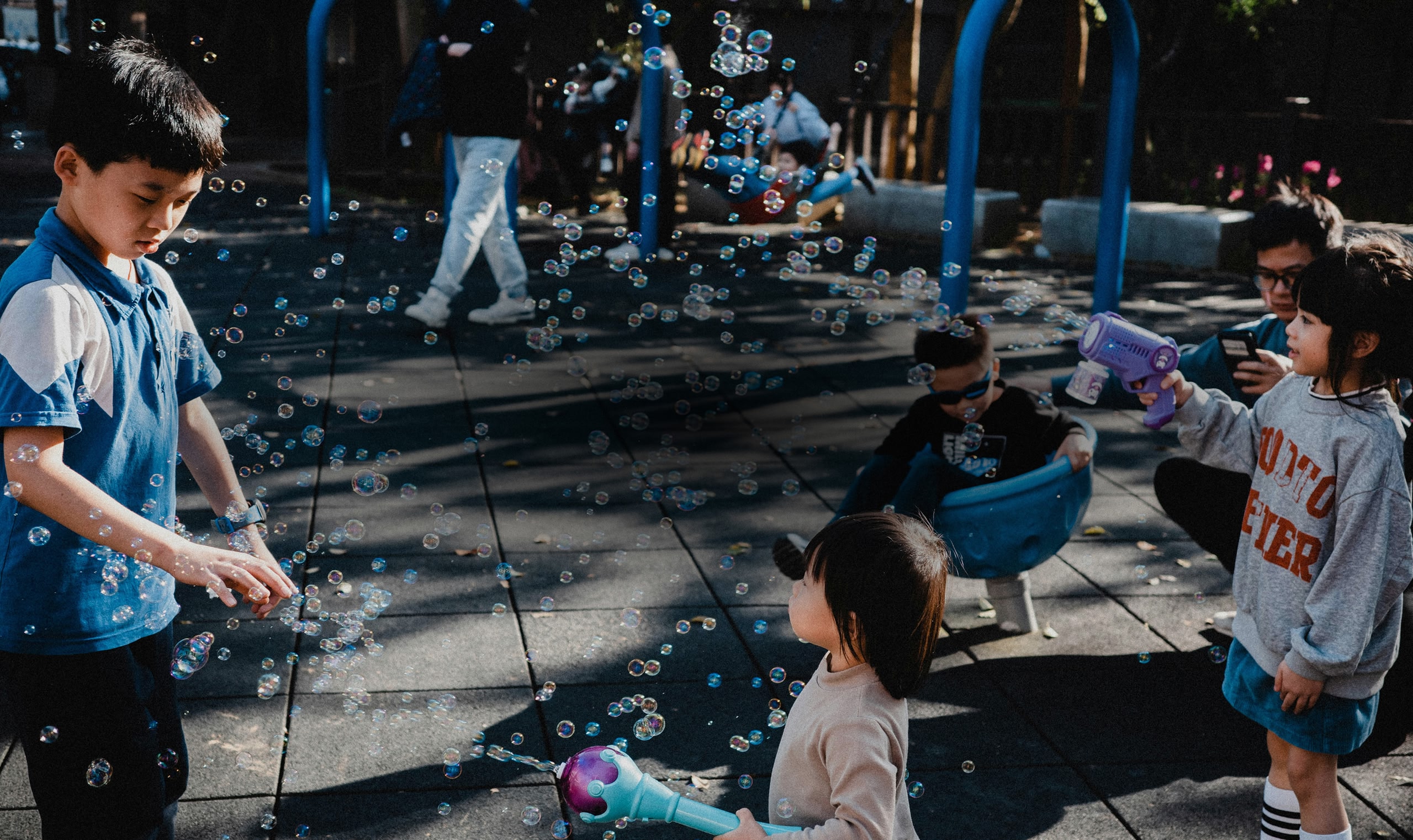 아이들이 활기찬 놀이터에서 비눗방울 총을 가지고 노는 모습.