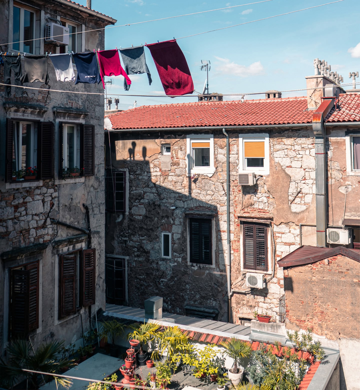 Kleidung trocknet an einer Wäscheleine über einem steinernen Innenhof in Rijeka, Kroatien.