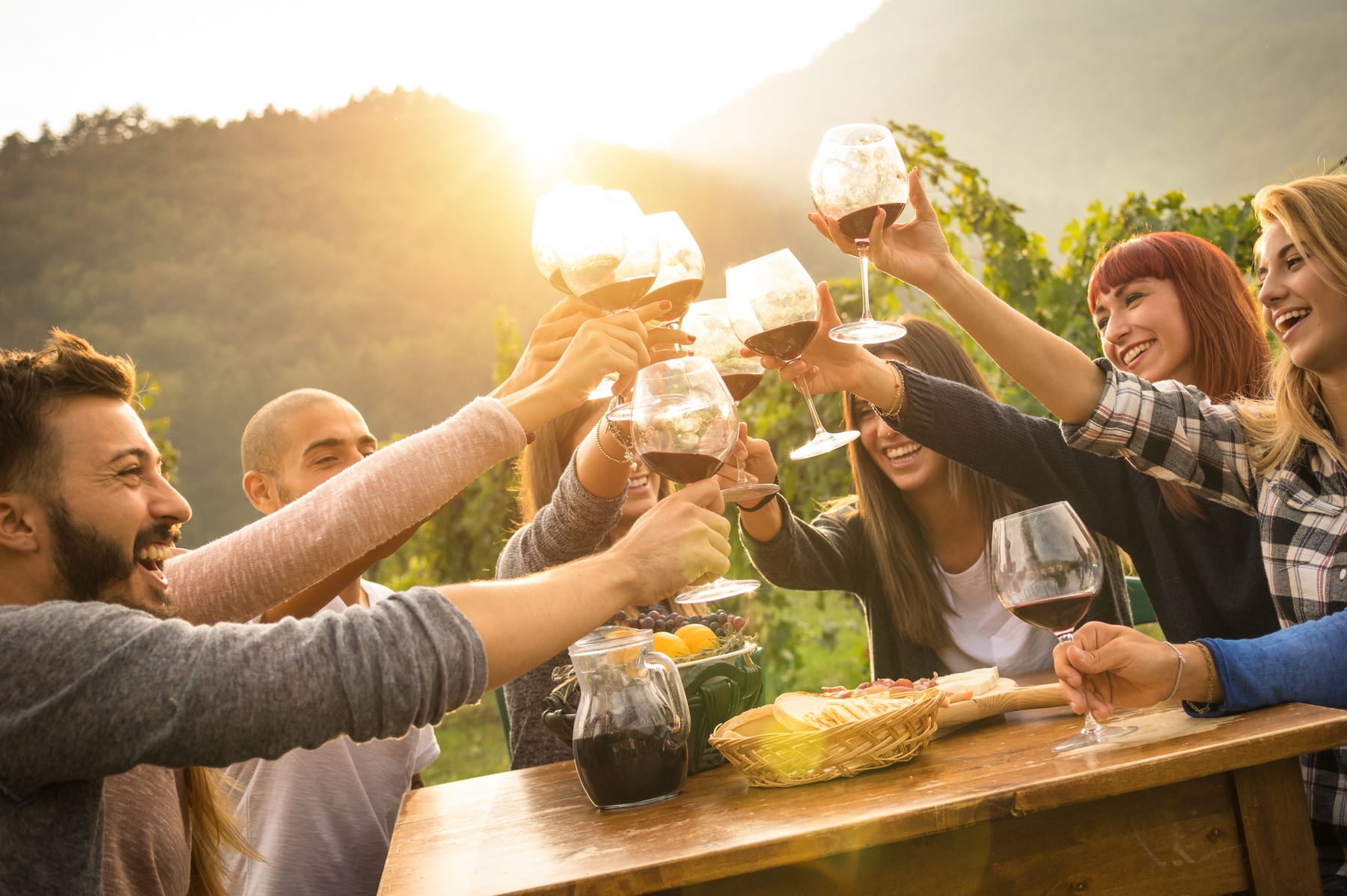 Group of friends celebrating and toasting their glasses of wine at a sunset dinner