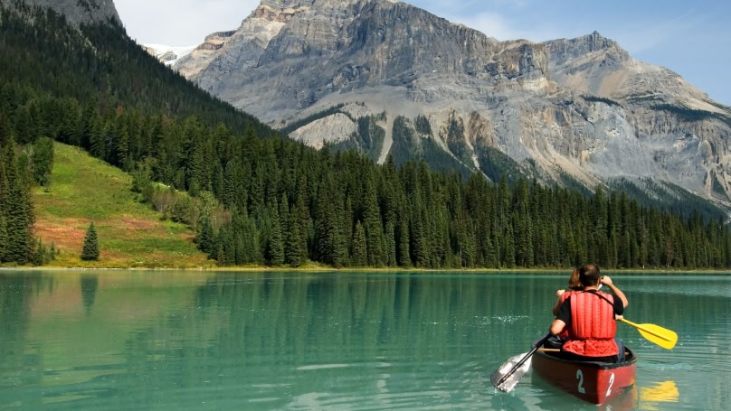 Um casal em uma canoa navegando por um lindo lago