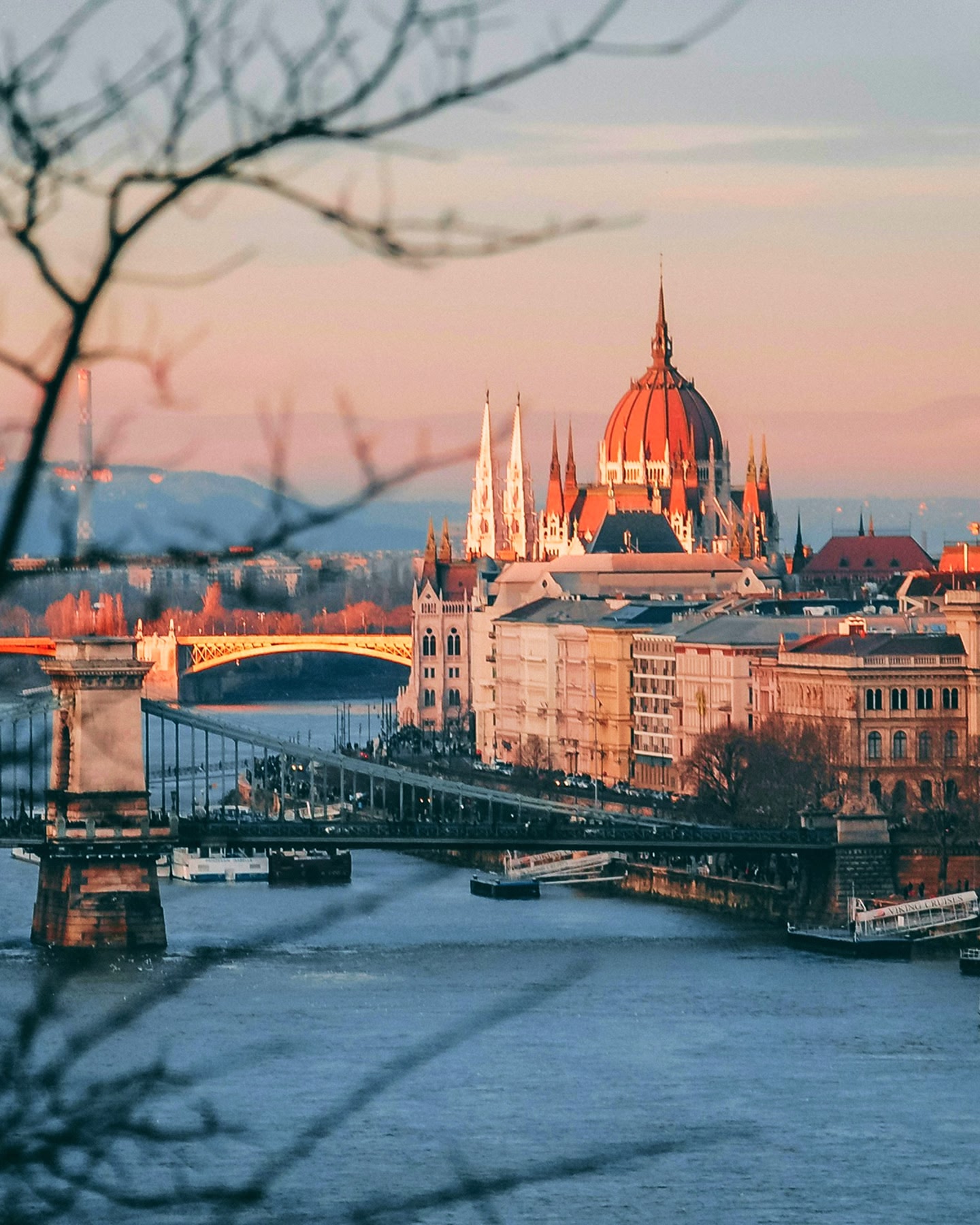 Das ungarische Parlament in Budapest erstrahlt über der Donau, mit der Kettenbrücke in der Nähe.