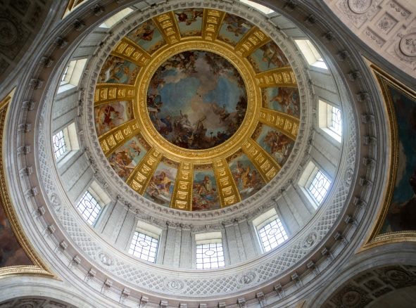 An image of the ceiling of a building with an artistic painting.