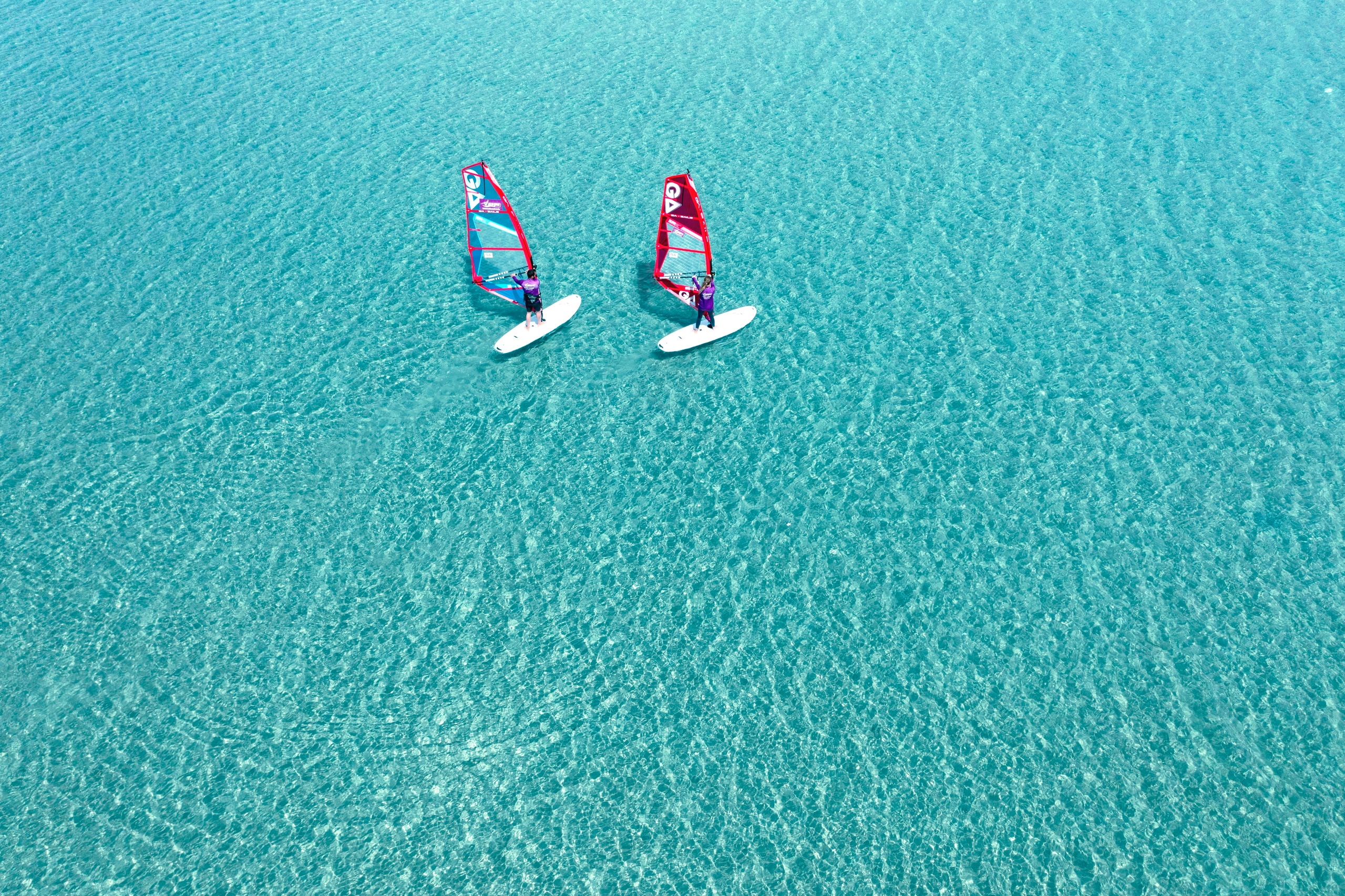 Deux kitesurfeurs sur l'eau bleue claire vue d'en haut.