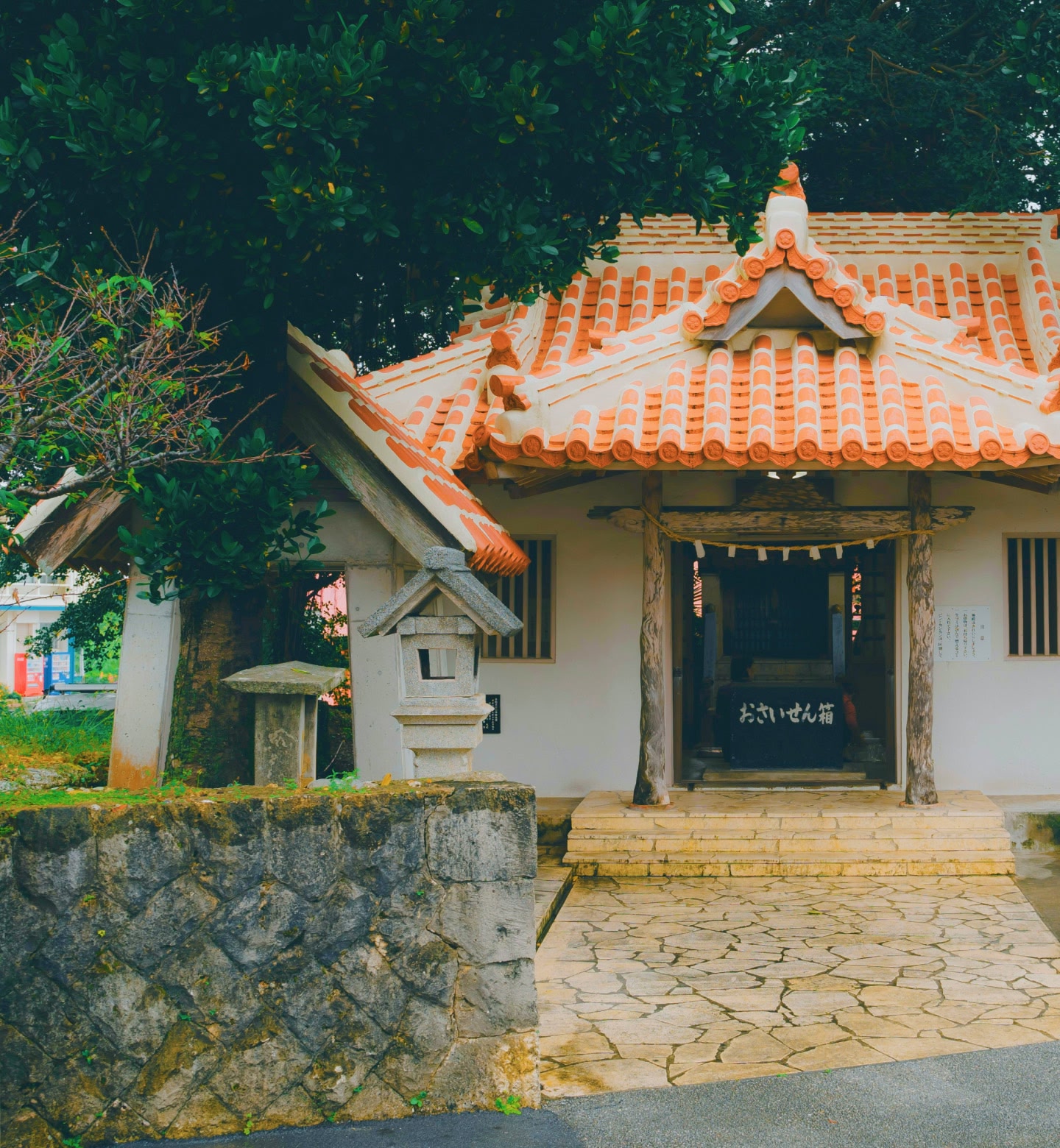 Un petit sanctuaire au toit de tuiles rouges niché à côté d'arbres à Miyako-jima, au Japon.