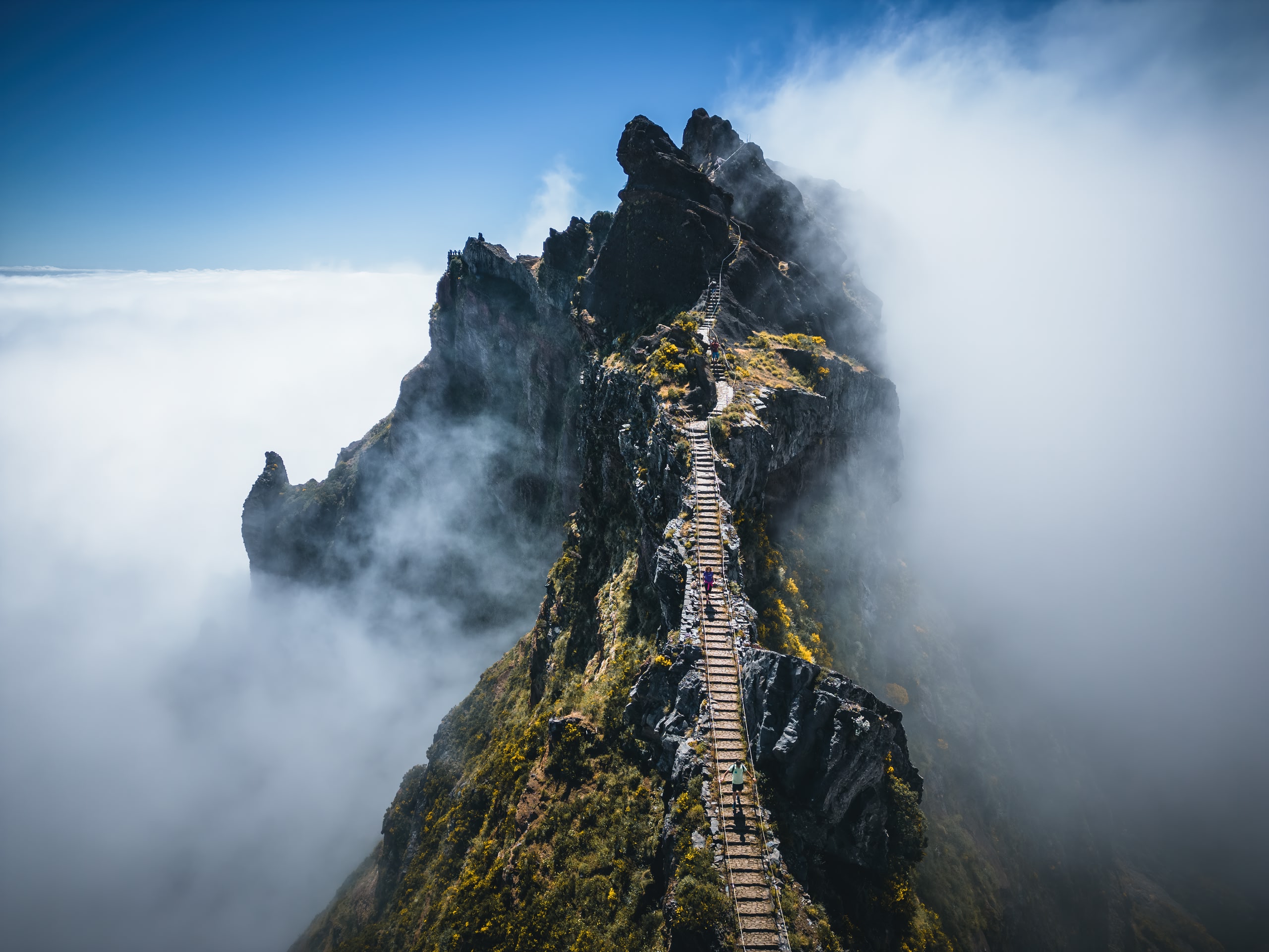 Misty mountain and aerial view of people hiking along a mountain in Madeira, Portugal. Blue sky.