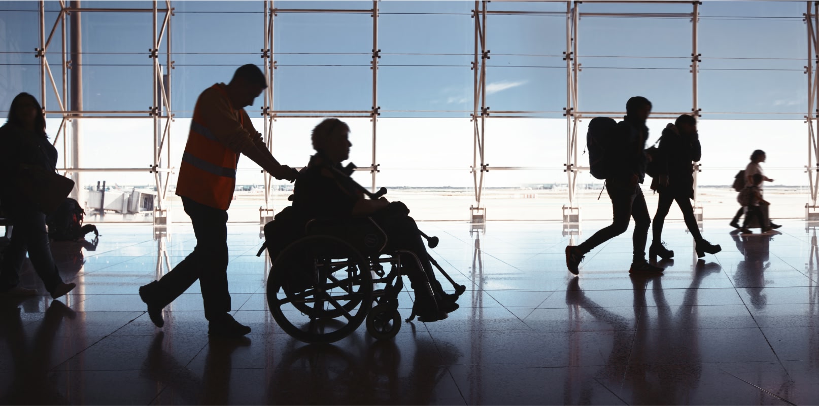 Image showing a wheelchair using passenger in an airport being assisted by a member of airport staff.
