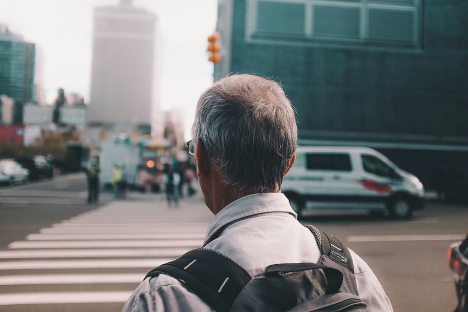 Homem com mochila nas costas indo atravessar uma rua na faixa de segurança - bagagem de mão GOL