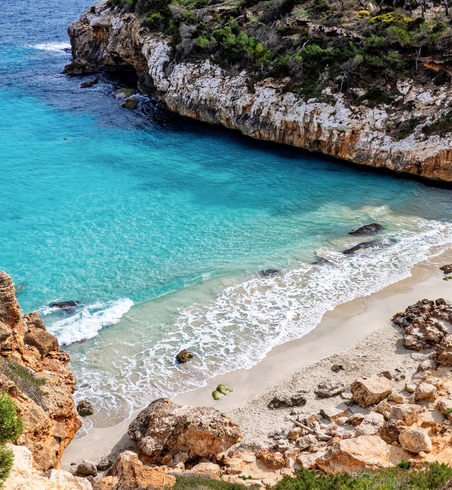 Une eau turquoise cristalline borde une crique de sable entourée de falaises près de Palma, en Espagne.