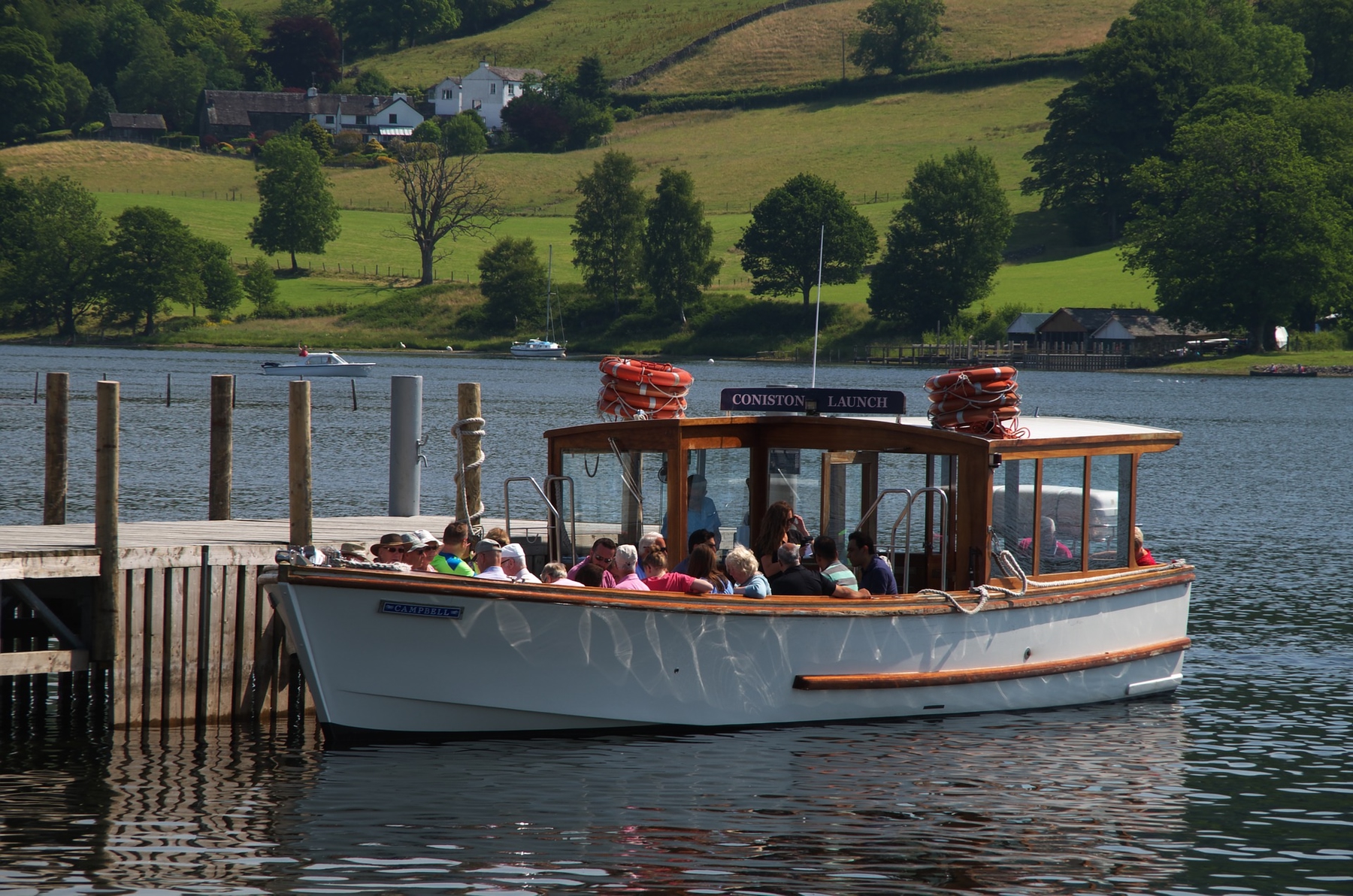 Tourists sitting on the Coniston Launch boat at the dock, about to take a trip on Coniston Water.