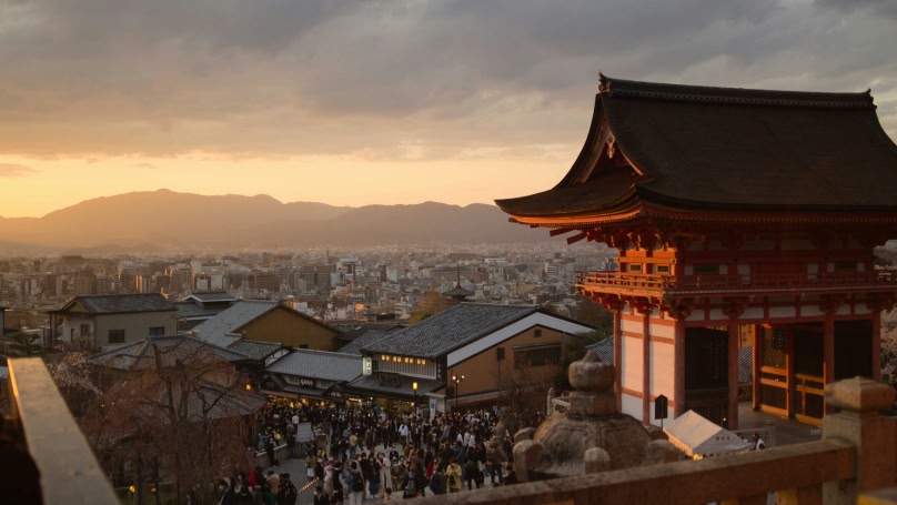 a temple gate with a crowd of people in front of it and mountains in the background