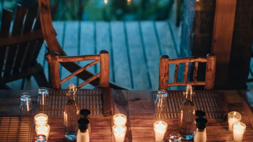 immagine di tavolo e sedie in legno con candele accese al buio