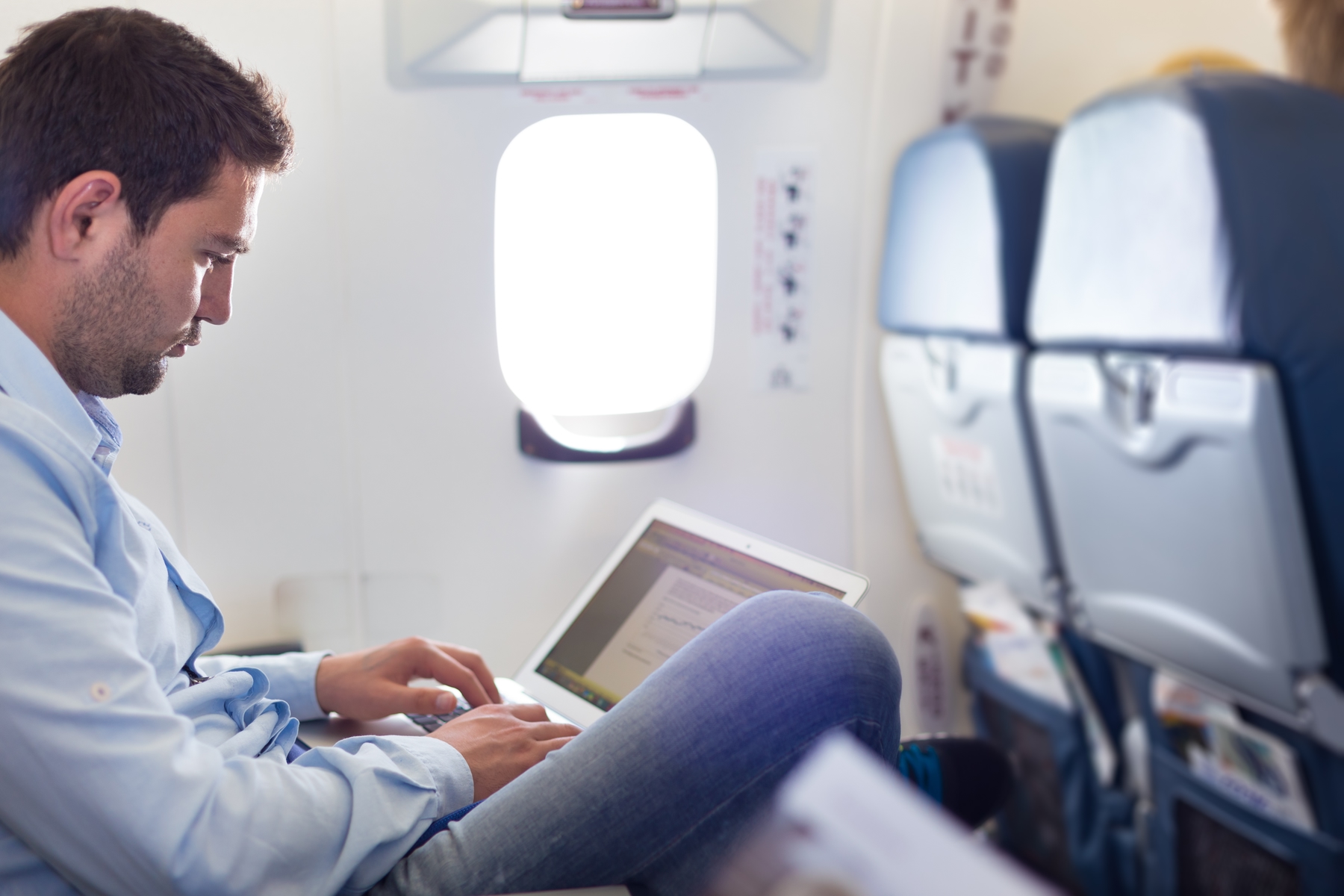Passageiro sentado confortavelmente em sua poltrona no avião. A ITA Linhas Aéreas também tem maior espaço entre os assentos.