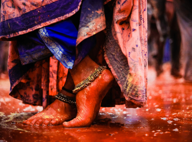 Vibrant and colorful close-up of a woman's feet adorned with bright red paint, celebrating the joyous Holi festival.