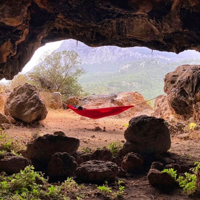 A red hammock strung up between two boulders outdoors.
