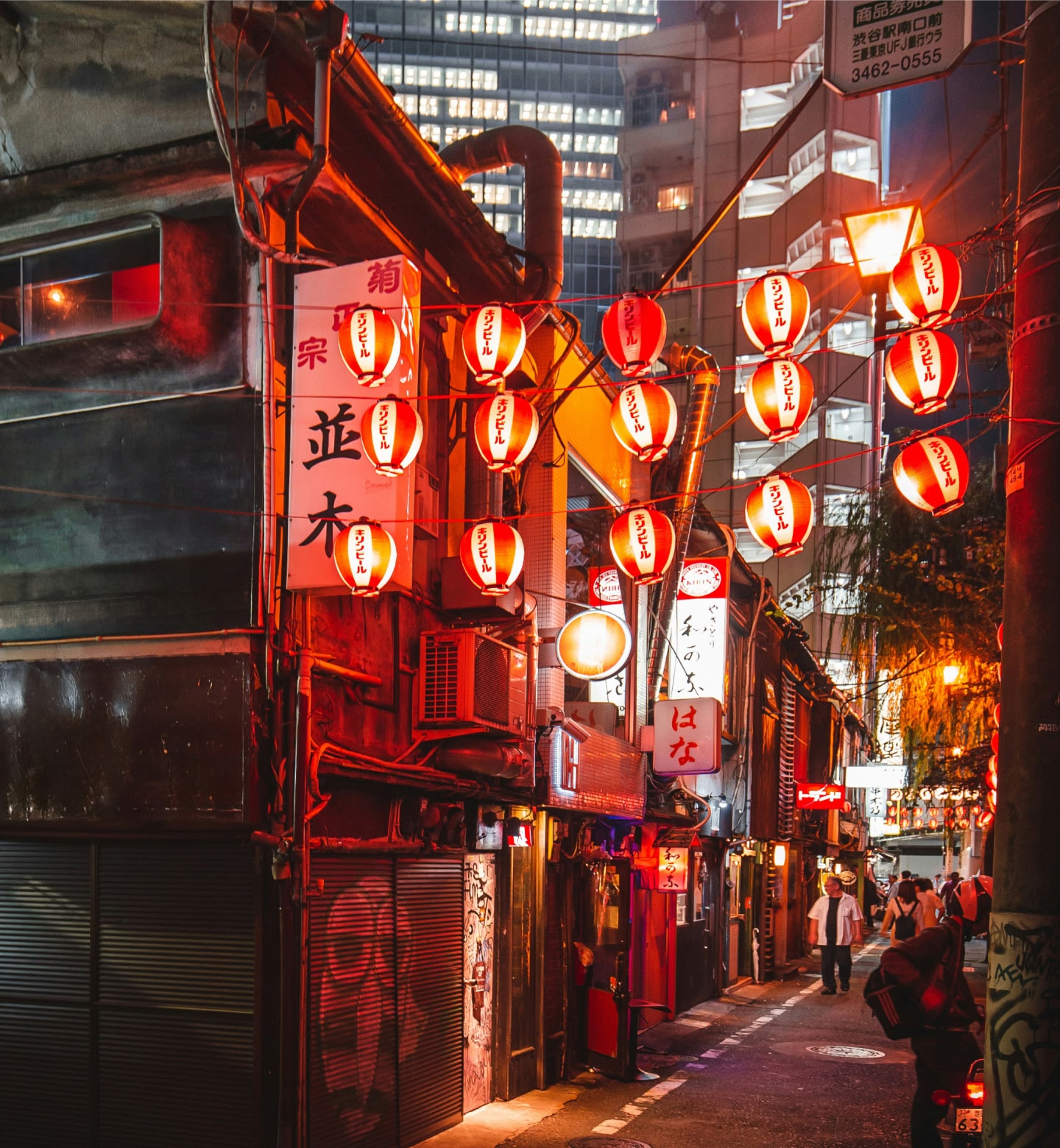 Linternas rojas brillan sobre un callejón estrecho en el distrito de vida nocturna de Tokio.