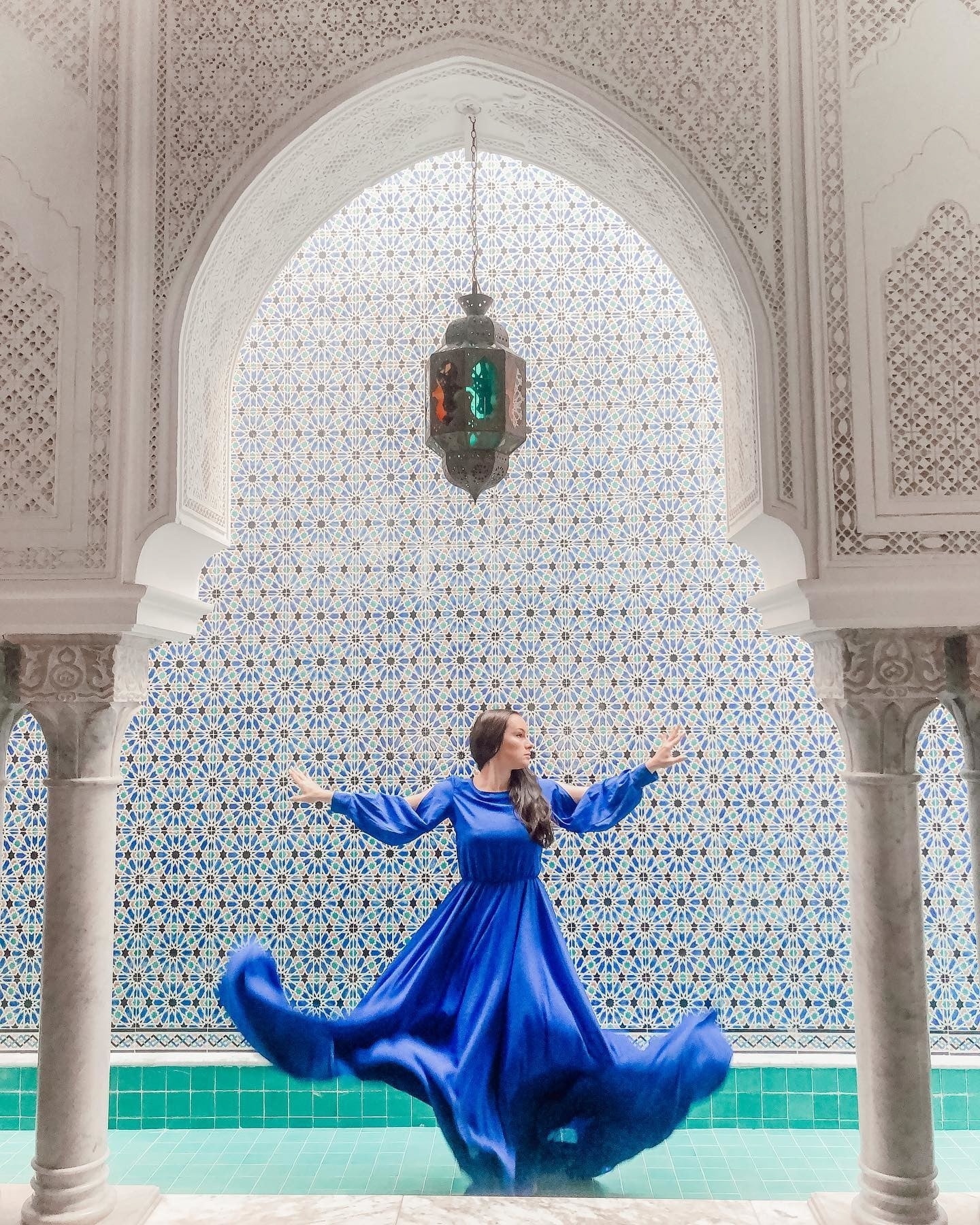 Frau in blauem Kleid inmitten eines typisch tunesischen Gebäudes