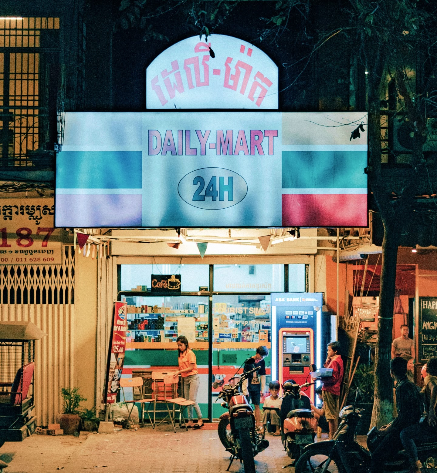 カンボジア、プノンペンの夜。煌々と灯りのともる24時間営業マートの外の人の群れ。