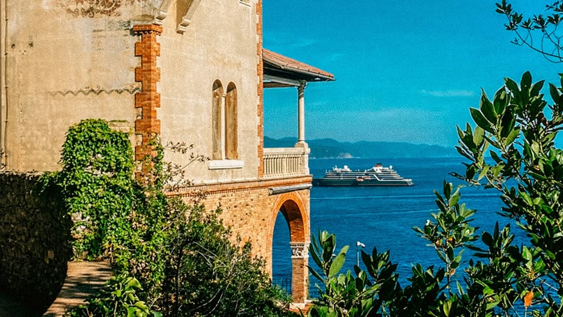 Edificio costiero con balcone che si affaccia sul mare e una nave da crociera.