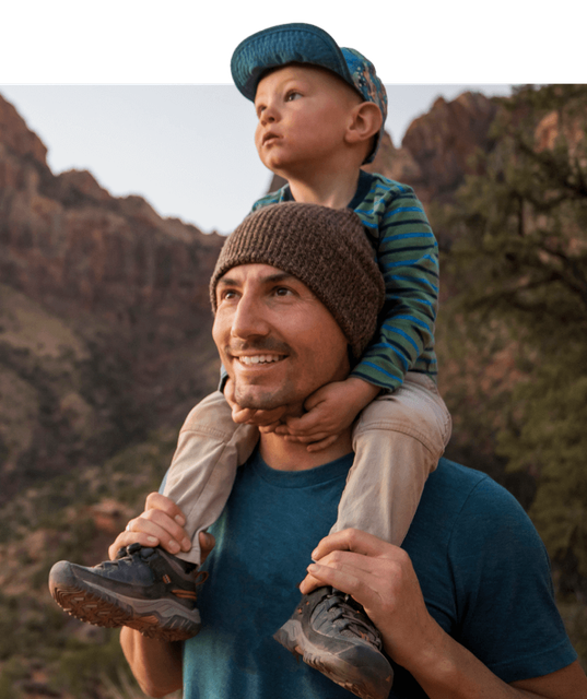 Child sitting on an adult's shoulders.