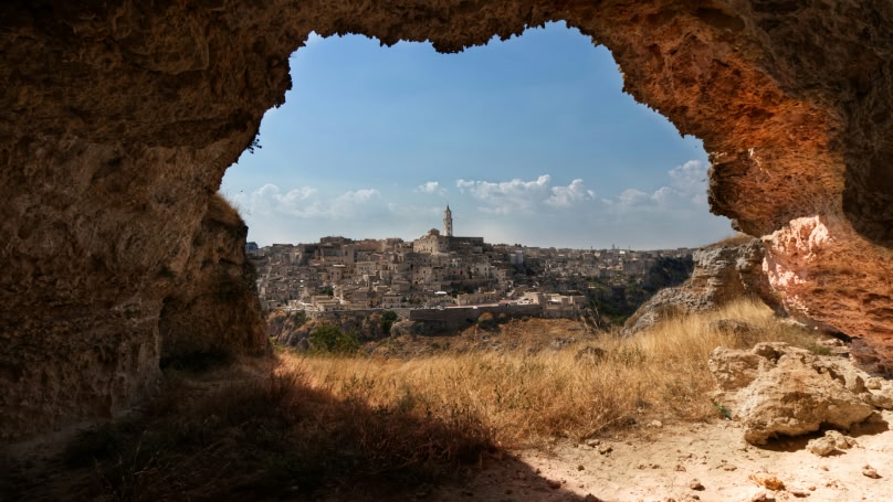 Città vista attraverso l'apertura di una grotta rocciosa.