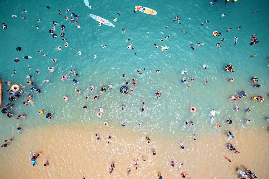 drone shot of people swimming at the beach