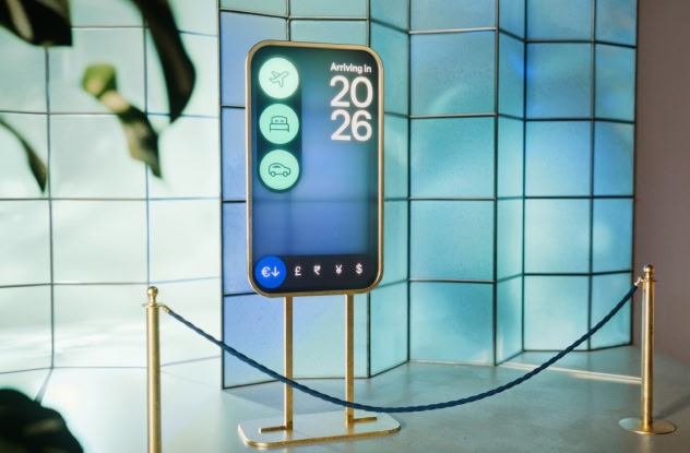 A futuristic travel kiosk displaying “Arriving in 2026” with icons for flights, hotels, car rental and currency symbols.