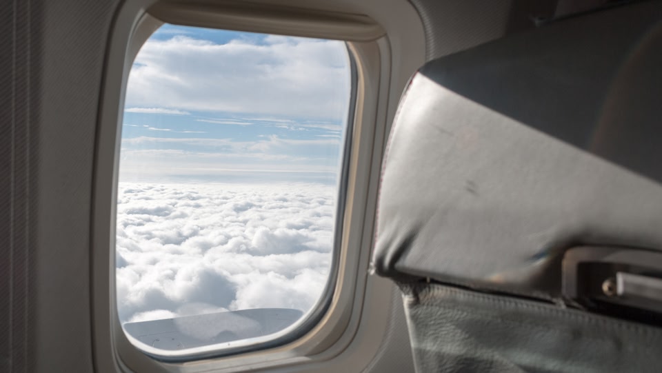 image d'une fenêtre d'avion avec des nuages ​​et un ciel bleu à l'extérieur de la fenêtre