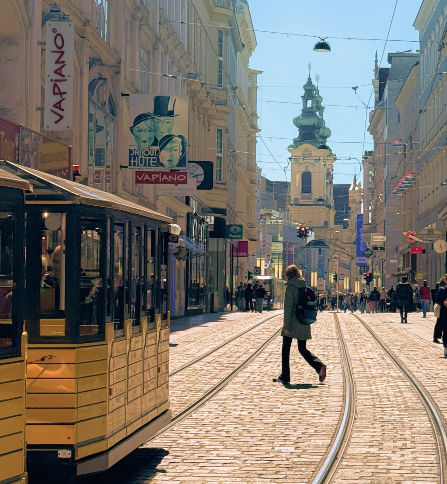 Un tram giallo che attraversa una strada pavimentata con ciottoli, fiancheggiata da edifici storici a Linz, in Austria.