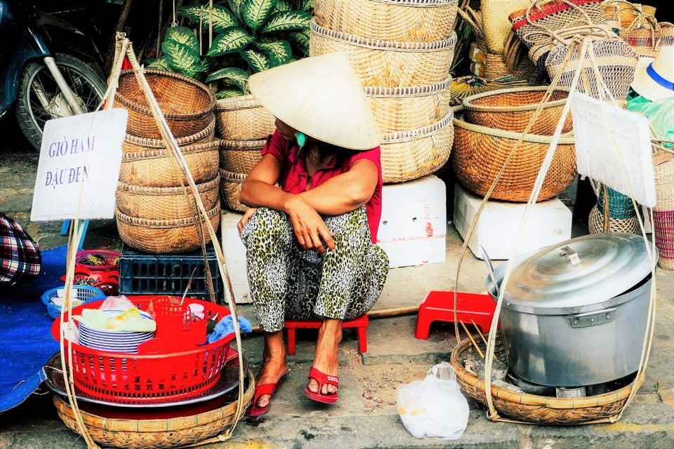 Woman in a traditional hat selling street food in Hoi An, a city near Da Nang.