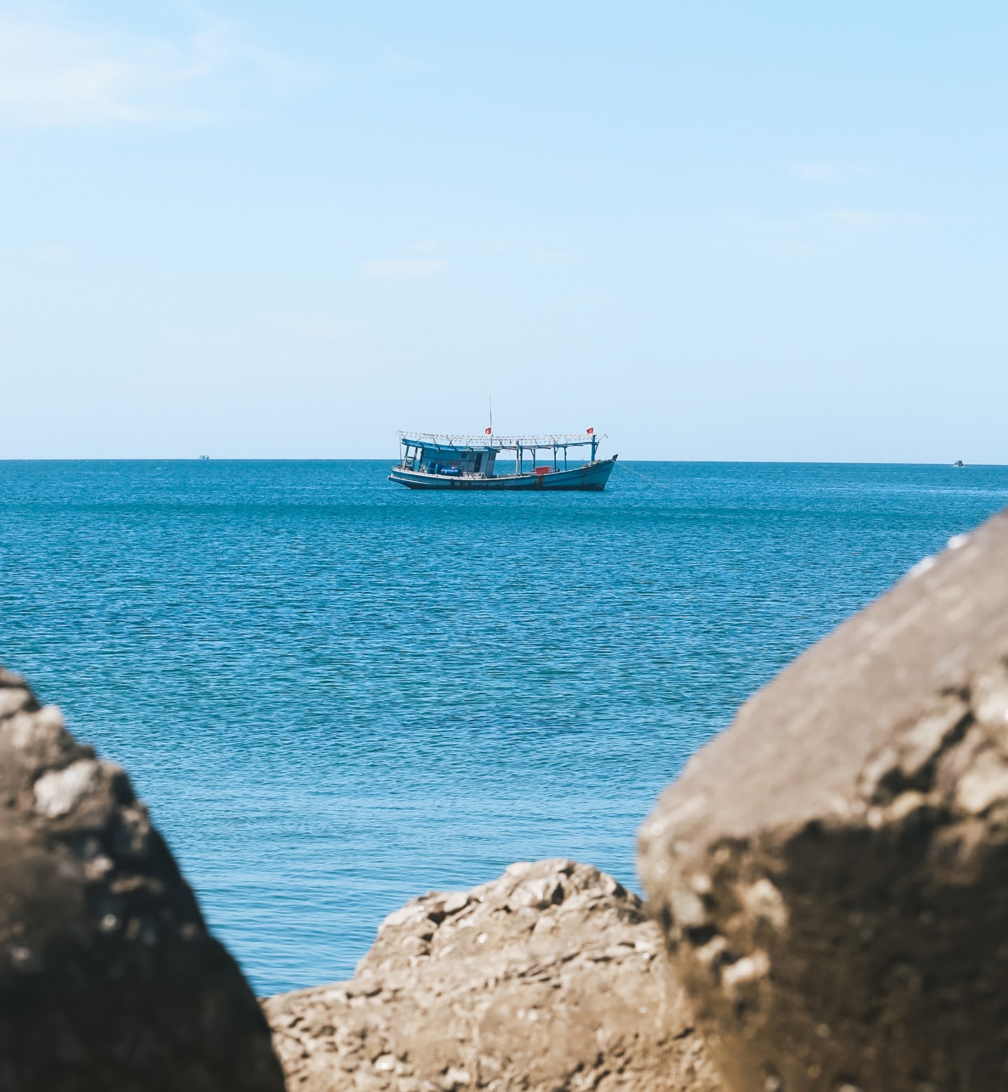 Un peschereccio che galleggia su calme acque turchesi, incorniciate da rocce al largo dell'isola di Phu Quoc, in Vietnam.