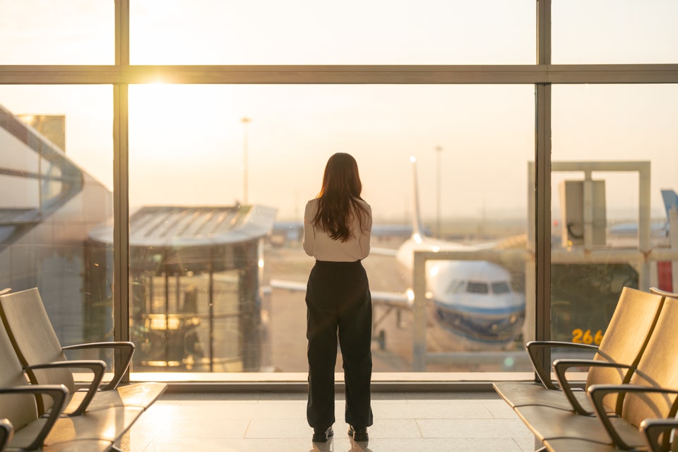 woman waiting at airport gate looking at plane