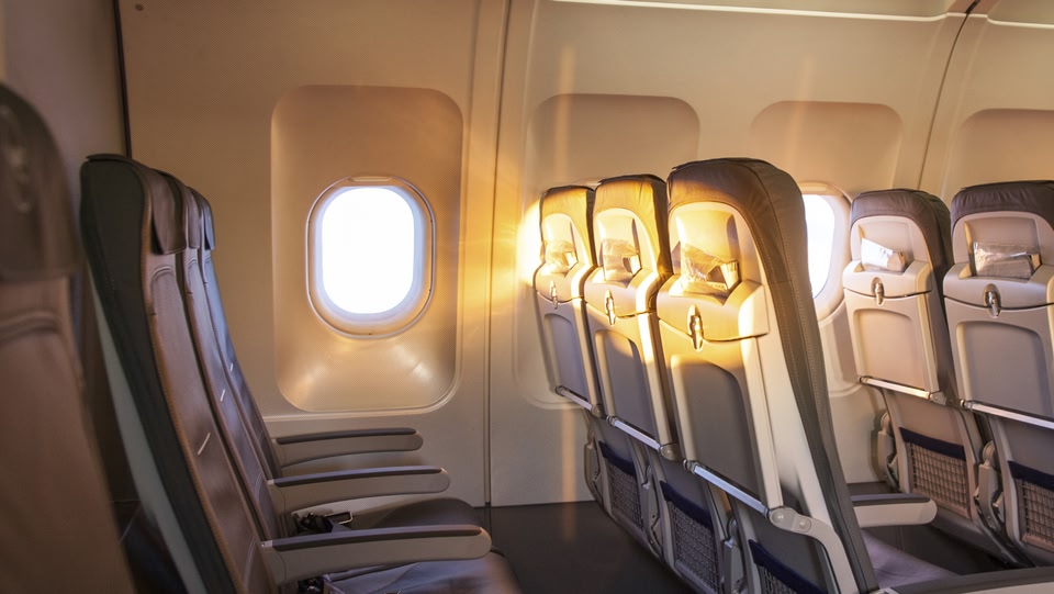image of a empty seats on a plane with the sun shining through the window