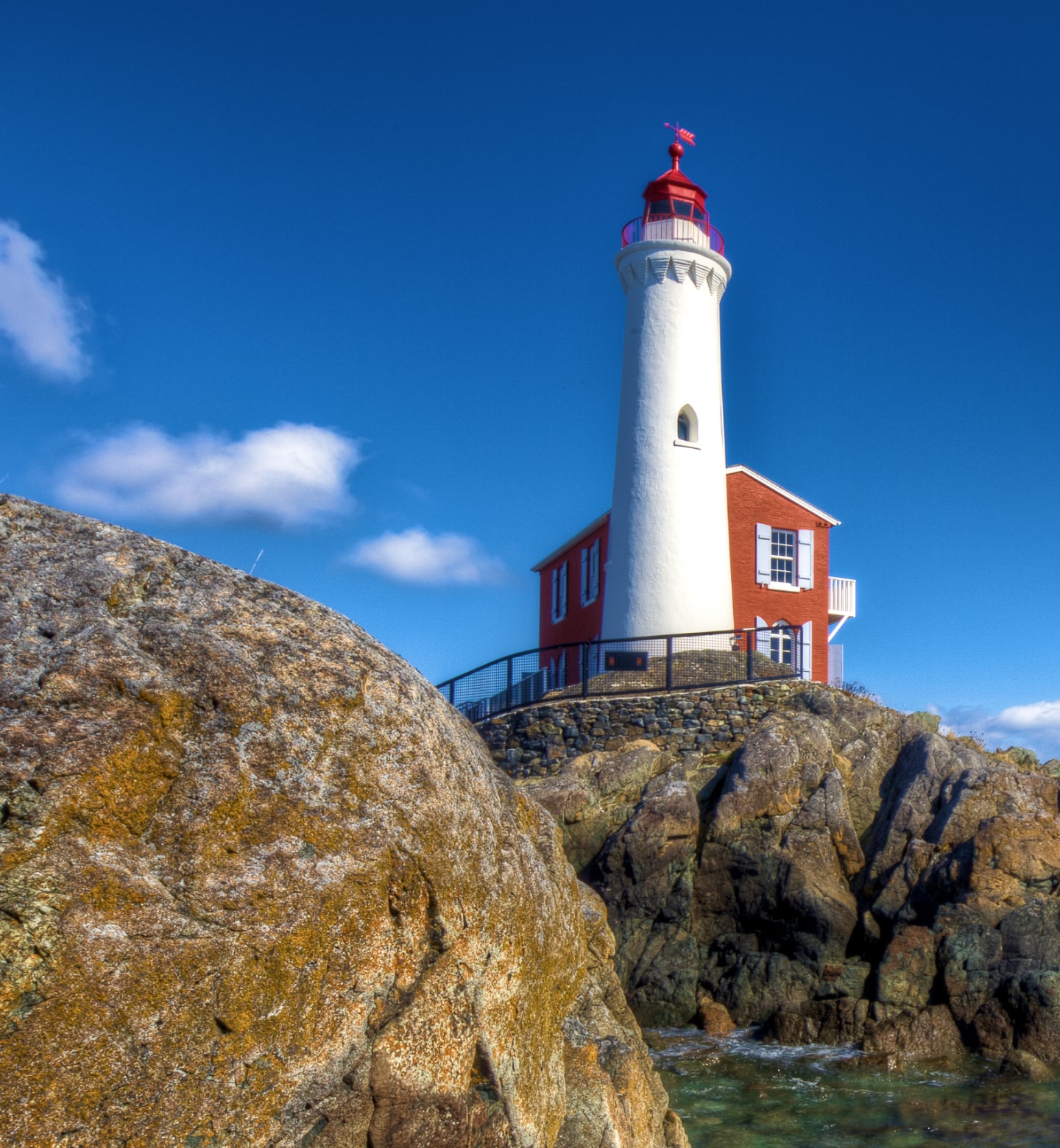 A lighthouse sits on top of a large rockface in Victoria, British Columbia.