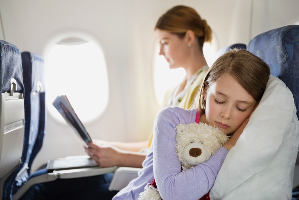 Girl sleeping with stuffed animal in airplane