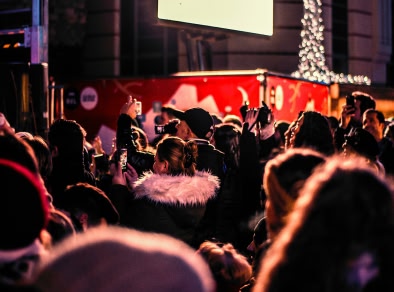 een menigte mensen die naar een kerstparade kijken