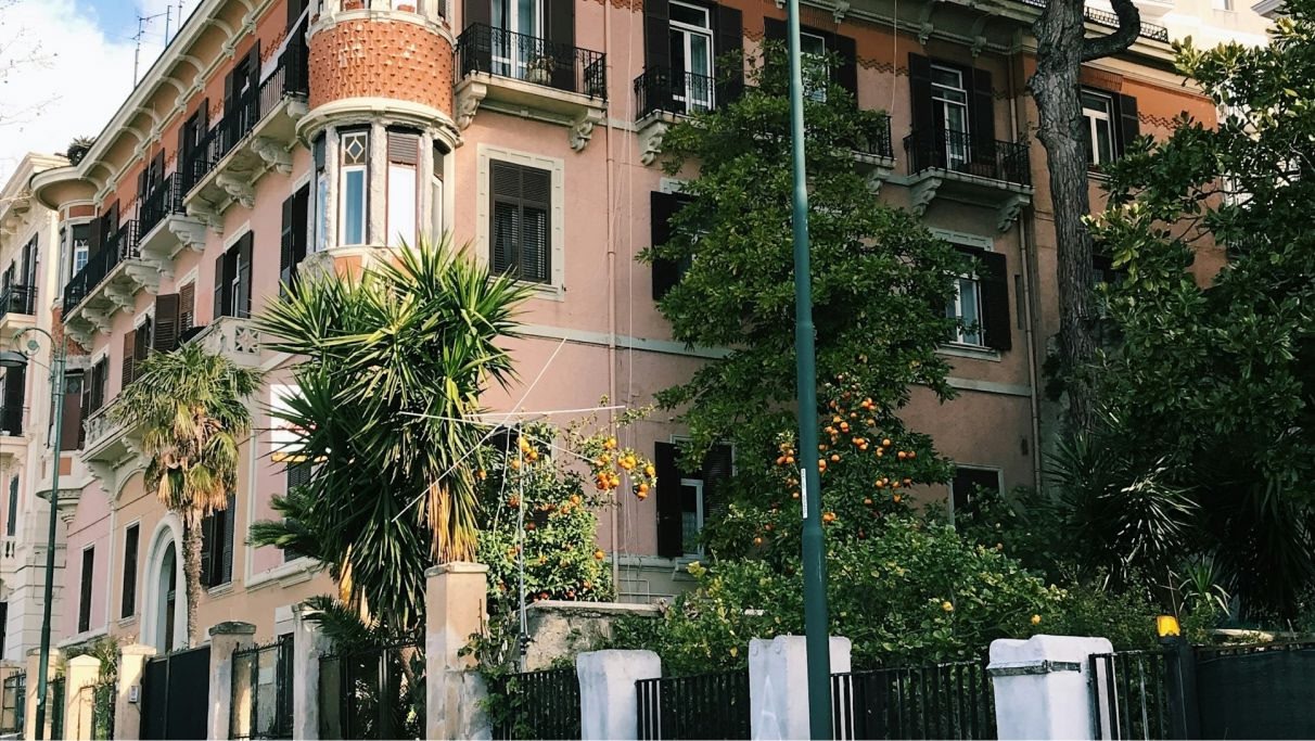 An image of Italian building surrounded by many plants