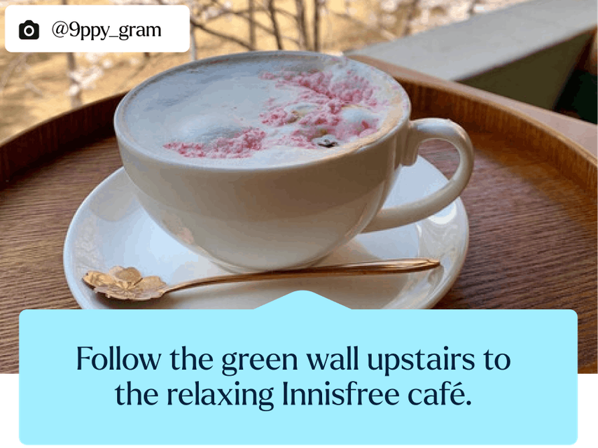 A close-up of a white coffee cup on a saucer and tray. Frothy coffee with delightful hints of pink in the foam.