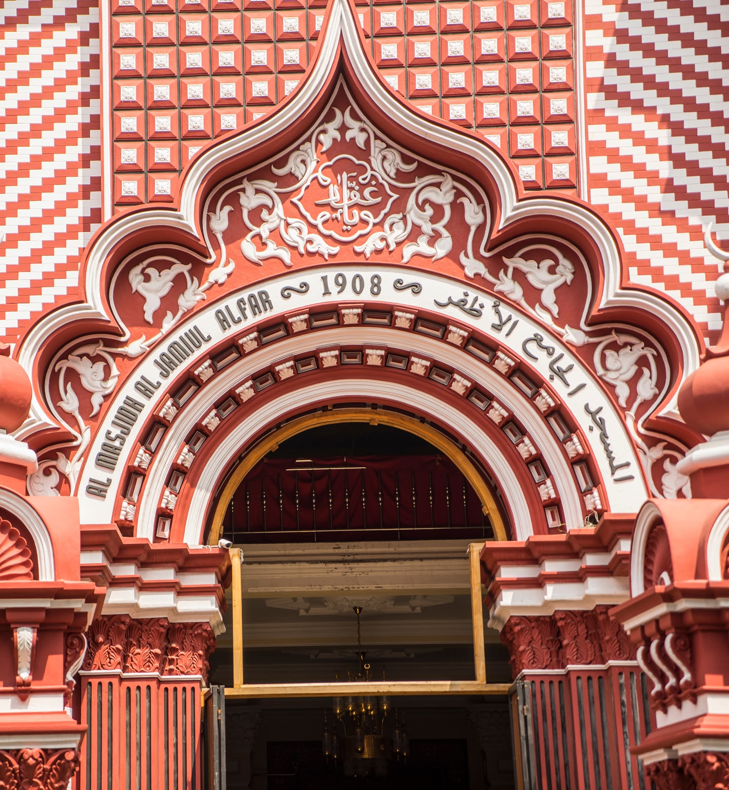 A close up of the entrance to Jami Ul-Alfar Mosque, showing its detailed red and white patterned architecture in Colombo, Sri Lanka