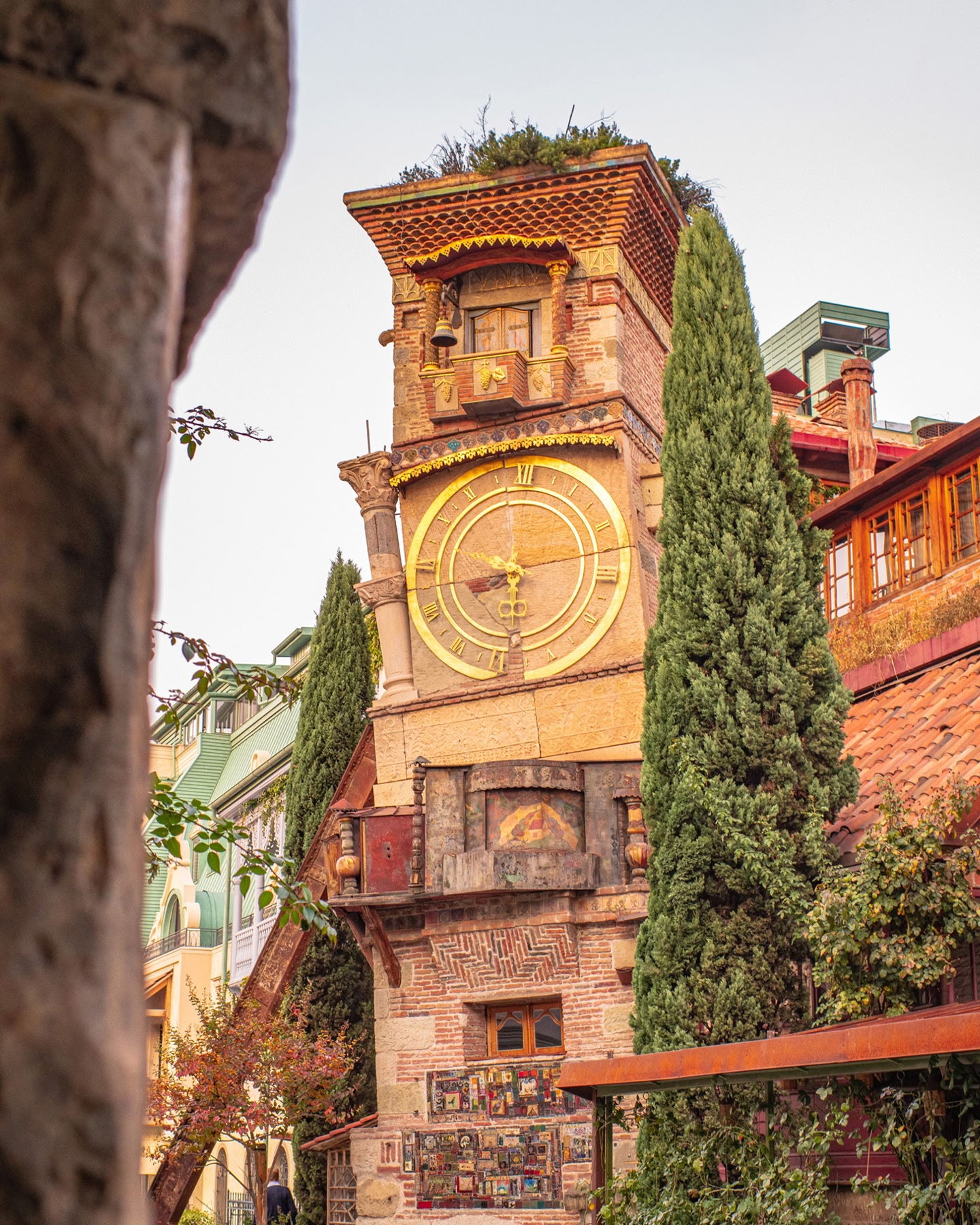 ジョージアのトビリシにある、金色の文字盤と傾斜した設計の歴史的なレンガの時計塔。