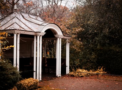 Un kiosque blanc entouré d'arbres dans un parc.