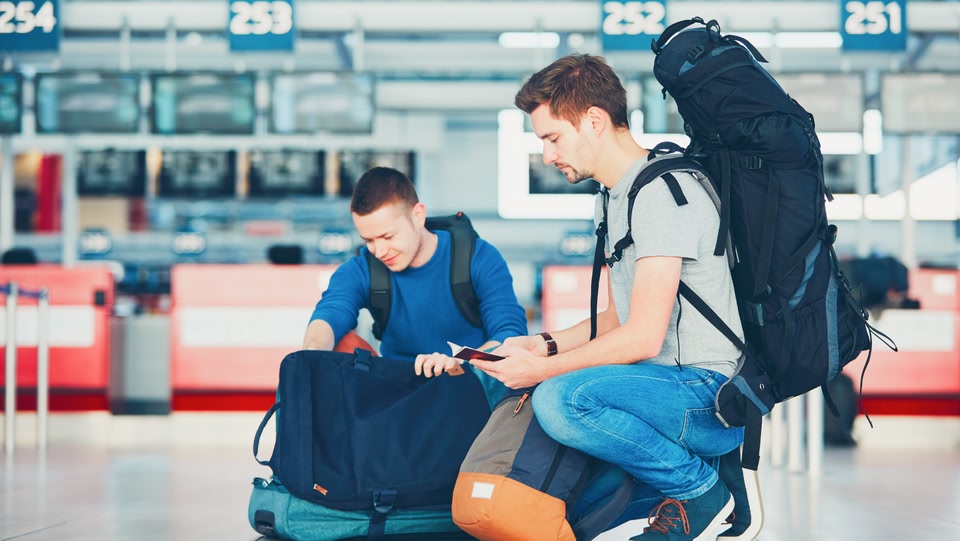  deux hommes se penchant sur leurs bagages à l'aéroport