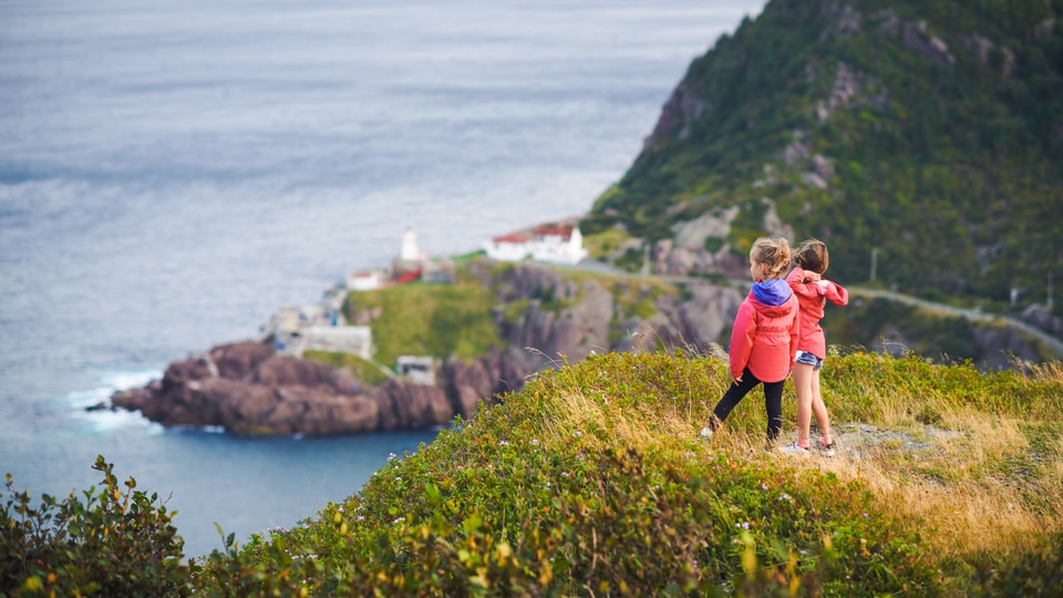 Two children standing on a grassy cliff overlooking the ocean in Saint John, New Brunswick, Canada.