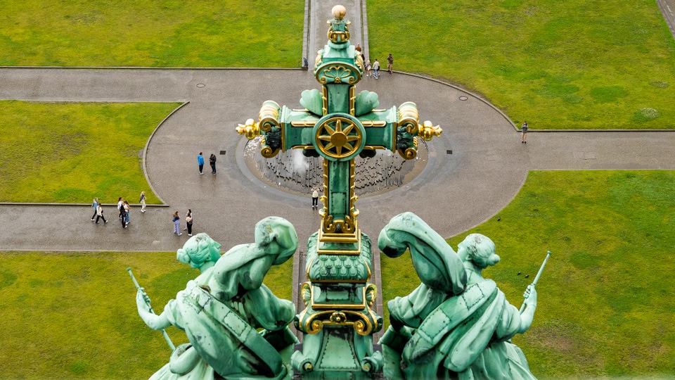Aerial view of a historic monument featuring intricate sculptures and green surroundings.