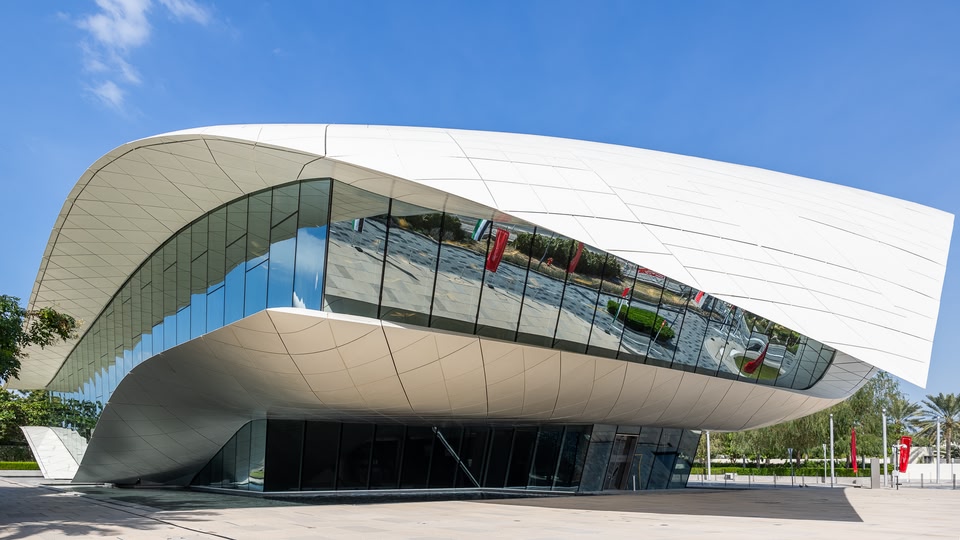Modern museum building with unique architectural design, featuring large glass walls and a curved white exterior.