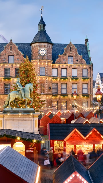 A historic museum building with a glass dome roof, situated near a reflecting pond with lush greenery around it.