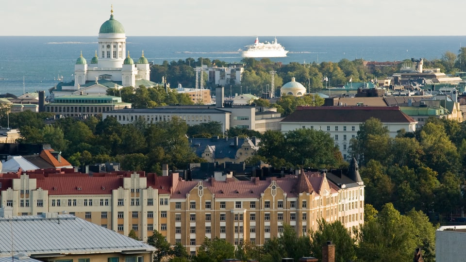 Aerial view of Helsinki skyline with a cruise ship on the sea in the background.