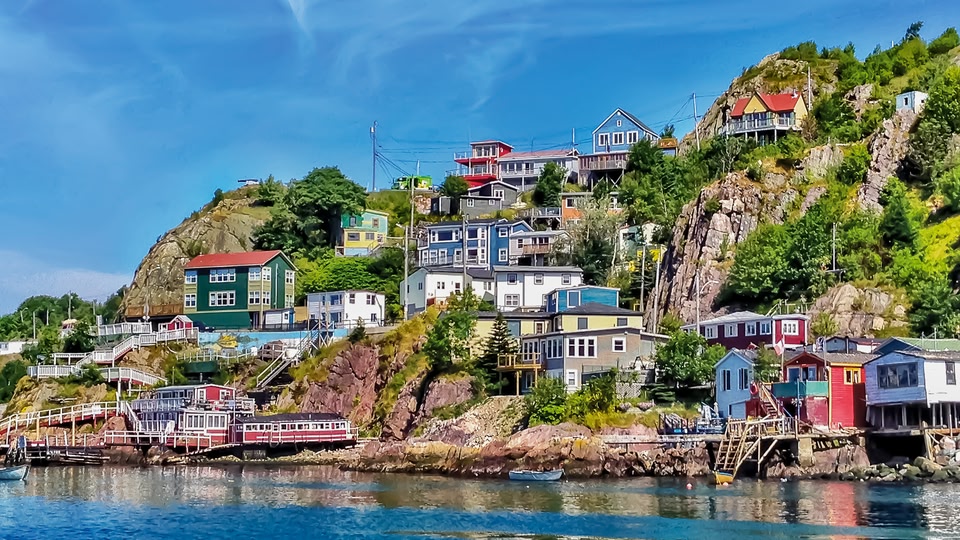 Colorful houses on a rocky hillside next to a body of water