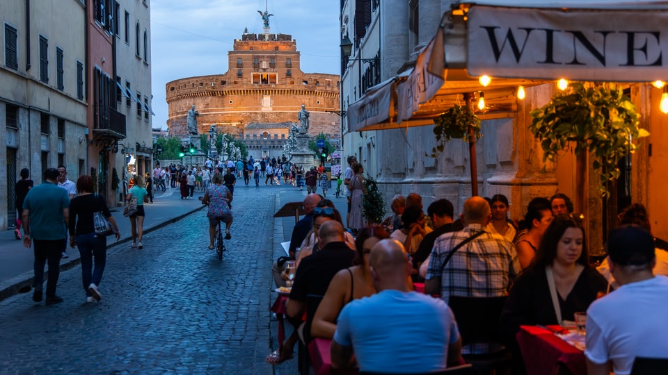 Outdoor dining area with people seated at tables under canopies in an historic district.