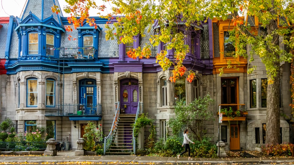 A row of colorful, historic buildings in Montreal, Quebec, with a woman walking on the sidewalk.